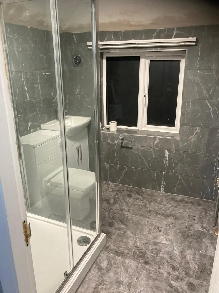 Completed grey tiled bathroom with shower enclosure
